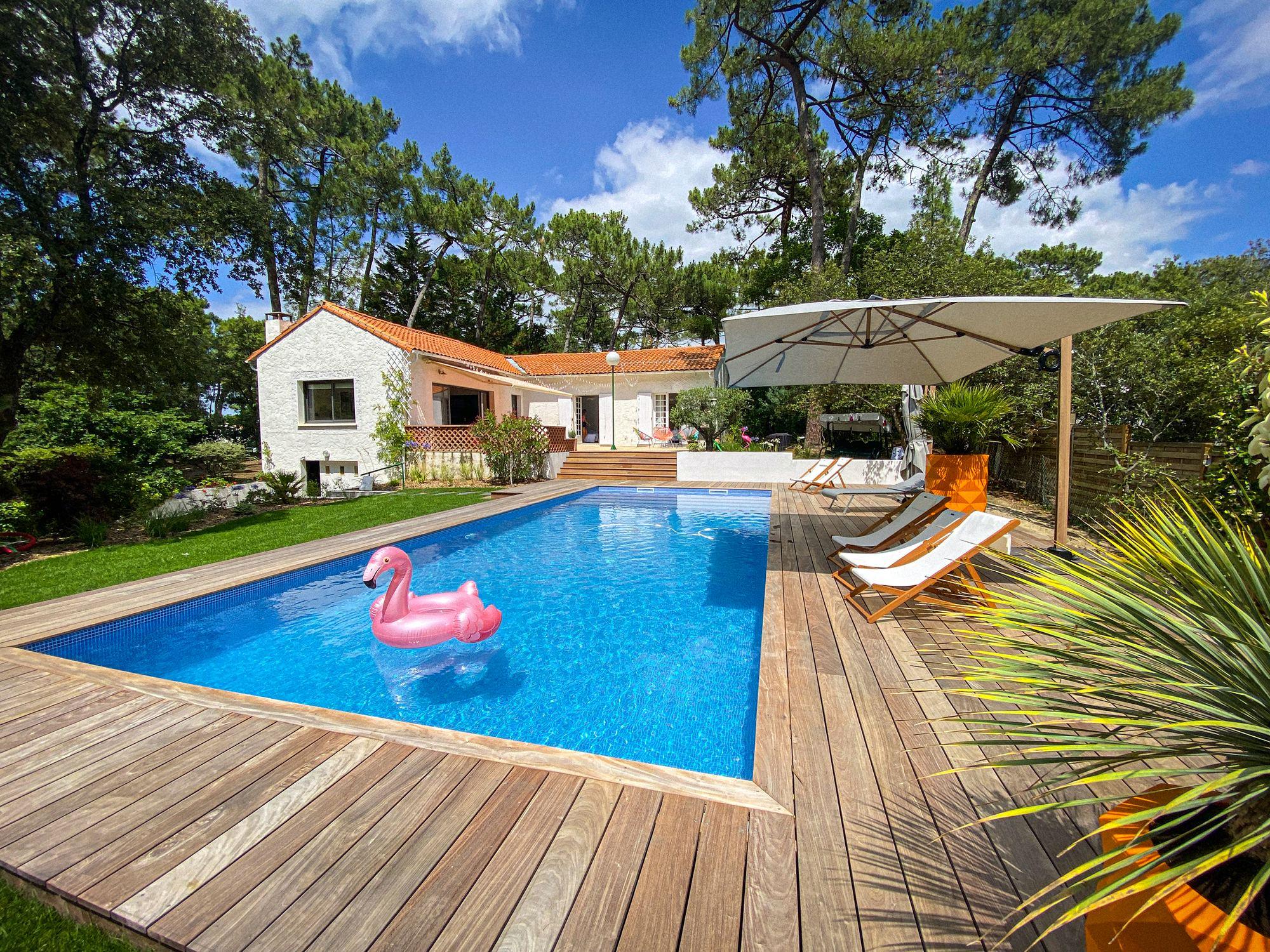 La piscine chauffée et la maison, entourées de pins